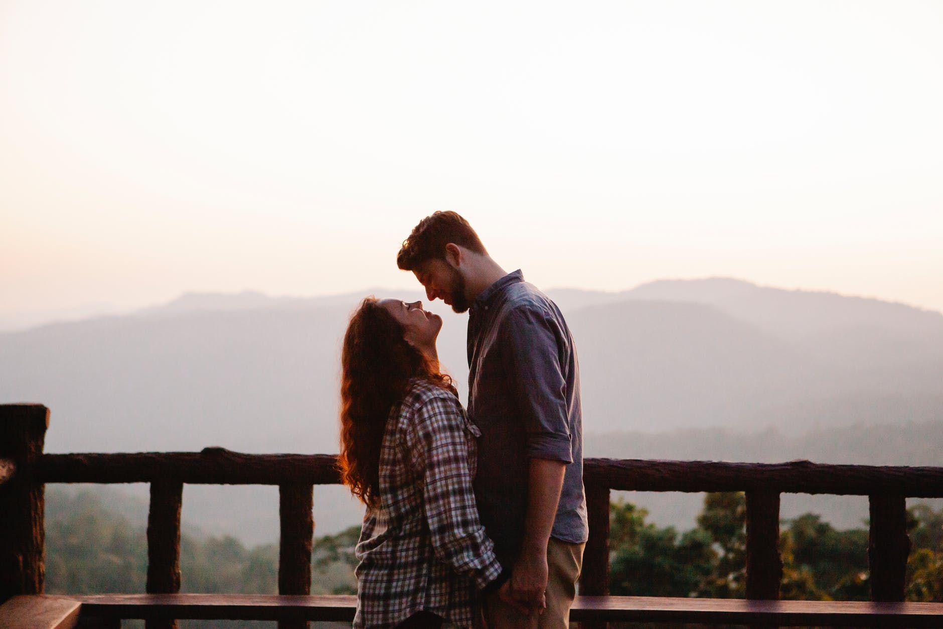 happy young couple holding hands on viewpoint during trip in highlands at sundown